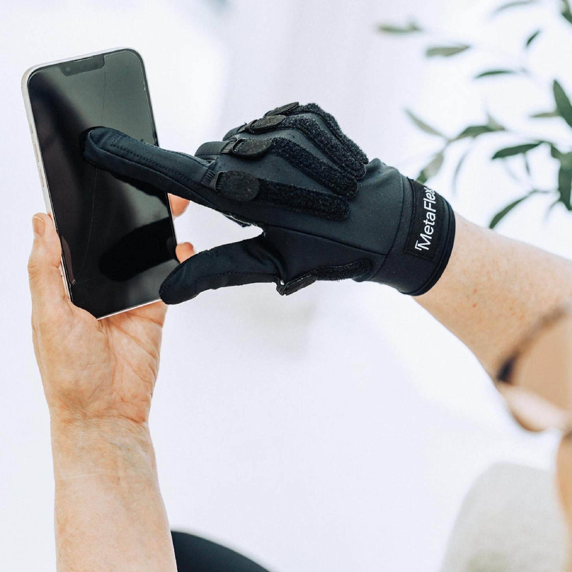 Senior swipes their phone unlocked easily wearing the comfortable MetaFlex grip strengthener compression gloves