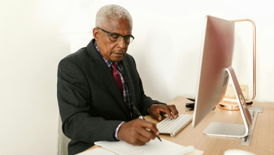 Man working at computer desk and writing